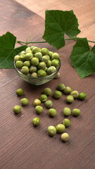 Fresh green peas in bowl on wooden background.