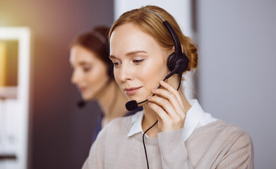 Businesswoman talking by headset in office. Call center and diverse people group in business