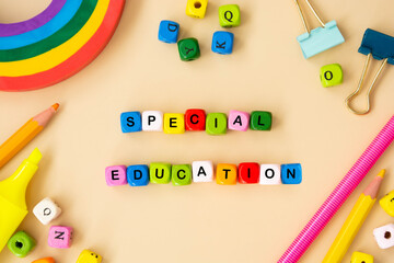 Special education words, child care, disability concept. Colorful office suplies flat lay with wooden cubes.