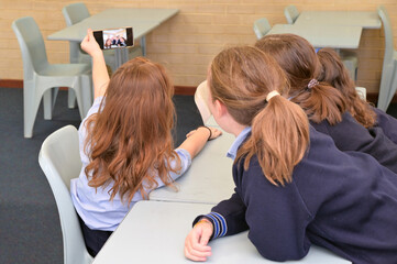 Naughty school girls taking a selfie in school classroom