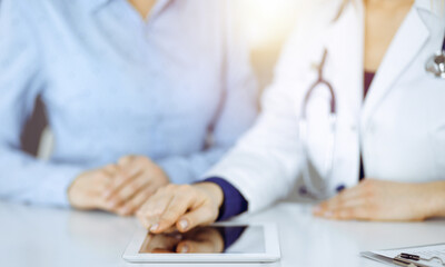 Unknown woman-doctor is showing to her patient a description of medication, while sitting together...