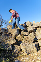 Naklejka premium a man works with a pile of stones and broken pieces of concrete, carries construction debris