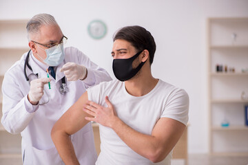 Young male patient visiting old doctor in vaccination concept