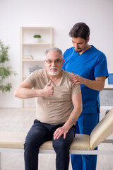 Obraz premium Old male patient visting young male doctor chiropractor