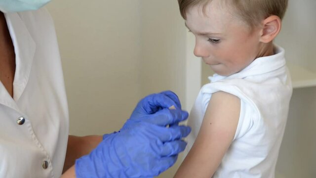 The child is sealed with a bactericidal plaster the injection site with the coronavirus or flu vaccine