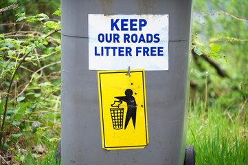 Keep roads litter free sign at roadside on wheelie bin