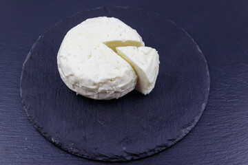 Soft Adyghe cheese on black slate background