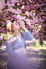 Obraz premium Spring portraits of a gorgeous young woman against a background of cherry blossoms. Japanese garden
