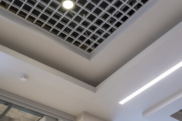 suspended and grid ceiling with halogen spots lamps and drywall construction in empty room in store...