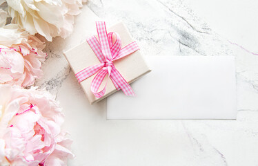 Pink peonies with empty  card and  gift box on  white marble background