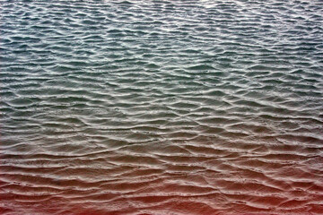 Abstract water surface ripples background in dark gold and green shades