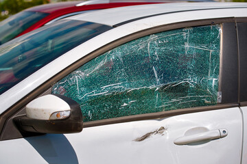Damaged door and cracked side car window glass of parked vehicle. Smashed car window. Broken shattered glass of side car window. Criminal incident, broken vehicle side window. Street accident