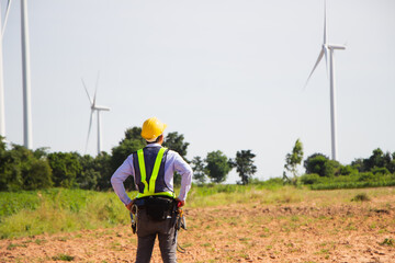 rear view man engineer wearing Personal protective equipment working in wind turbine farm background copy space