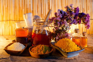 Closed up organic honey in glass bowl with spa salt, fragrance dry flower, thanaka and turmeric powder, with aroma gel and soft white and yellow towel in spa shop
