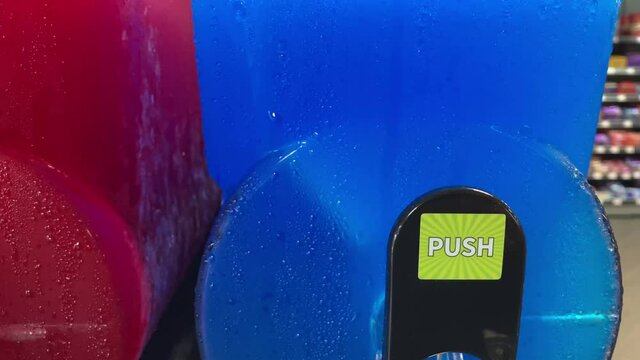 Summer drink: ice cold blue and red slushy in a dispenser covered in fresh condensation drops

