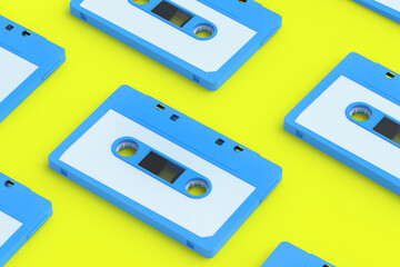 Fototapeta premium Rows of vintage audio cassettes tape of blue color on yellow background. Music storage. Retro cartridge. 3d render