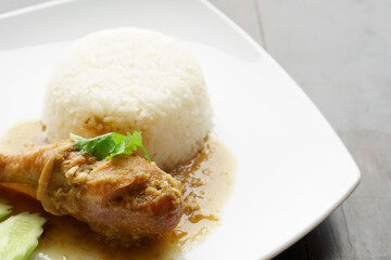 Baked chicken drumstick rice juicy with cucumber and coriander or green vegetable on white dish and black wooden table for breakfast or lunch and dinner food in restaurant or food court with copyspace