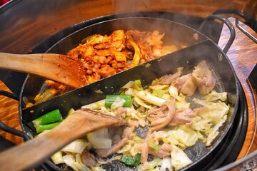 "Dak Galbi" one of the popular Korean dishes, stir fried vegetables, chicken and Korean curry (Gochujang) in a large hot pan.