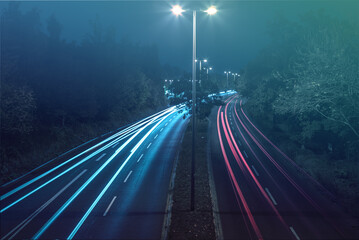 Long-exposure shot of a four-lane road with luminescent lights at the approach