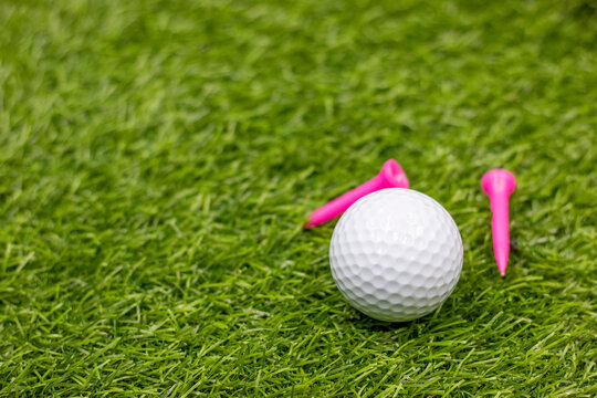 Golf ball with pink tee on green grass for Breast Cancer Awareness