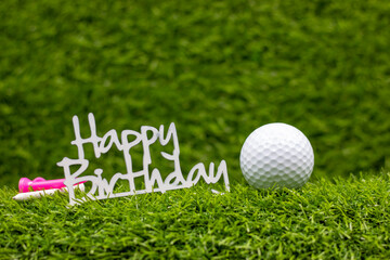 Golf ball with word happy birthday is on green grass