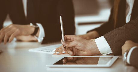 Unknown businessmen and woman sitting, using laptop computer and discussing questions at meeting in modern office, close-up