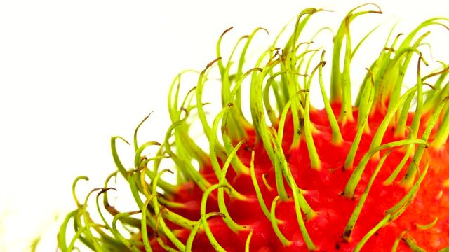 4K  whole red freen color rambutan fruits and one peeled rambutan. Rotating on the turntable isolated on the white background. Close up. Macro