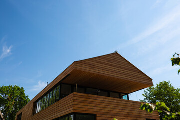 modern wooden house with wooden roof, blue sky