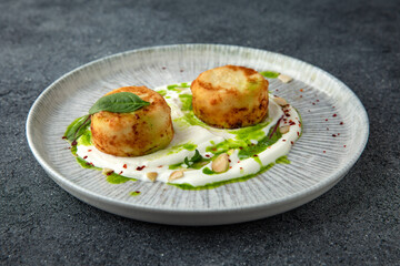 Lush cheesecakes with spinach and yoghurt and almond sauce. Healthy nutritious breakfast. Ready menu for the restaurant. Neutral gray blue textured background