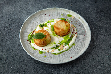 Lush cheesecakes with spinach and yoghurt and almond sauce. Healthy nutritious breakfast. Ready menu for the restaurant. Neutral gray blue textured background