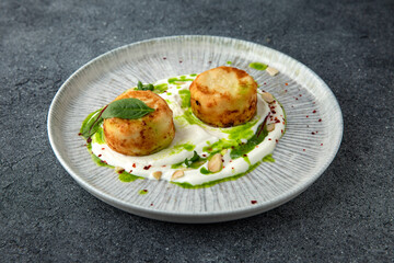 Lush cheesecakes with spinach and yoghurt and almond sauce. Healthy nutritious breakfast. Ready menu for the restaurant. Neutral gray blue textured background