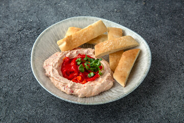 Hummus with baked bell peppers. Ready menu for the restaurant. Neutral gray blue textured background