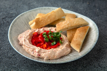 Hummus with baked bell peppers. Ready menu for the restaurant. Neutral gray blue textured background