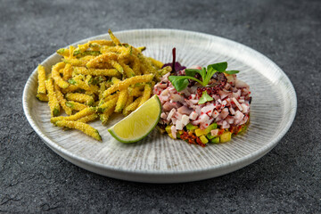 Octopus tartar with avocado and tender zucchini in batter. Ready menu for the restaurant. Neutral gray blue textured background