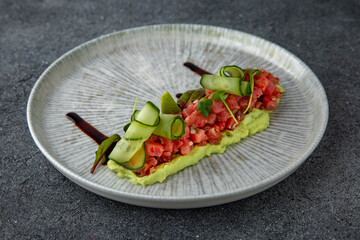 Guacamole salad, fresh tuna, cucumbers, tobiko caviar. Ready menu for the restaurant. Neutral gray blue textured background.