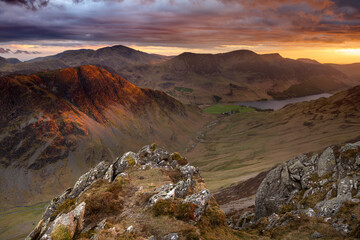 Stunning panoramic view of Cumbrian mountains with dramatic sunset in sky. Taken from Dale Head looking down towards Newlands Pass and Buttermere in the background. Lake District, UK.