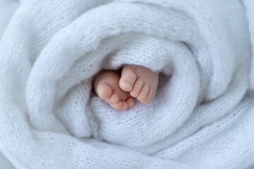 newborn baby's legs wrapped in white soft cloth close up