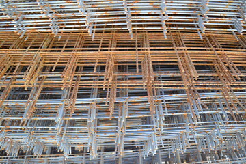 Stacks of square metal and rusty reinforcement bars and mesh for building construction. The reinforcing frame of the base plate.Civil engineering. Construction site.Metal corrosion.