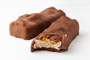 Two chocolate ice cream bars with caramel and peanuts on white background close up macro shot