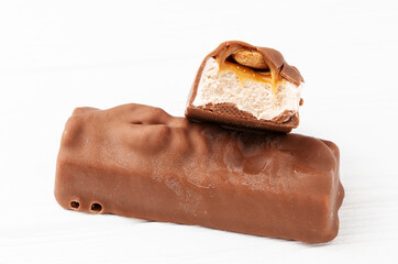 Two chocolate ice cream bars with caramel and peanuts on white background close up macro shot - obrazy, fototapety, plakaty