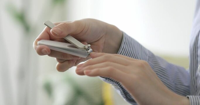 A woman's hand that cuts her nails with a nail clipper