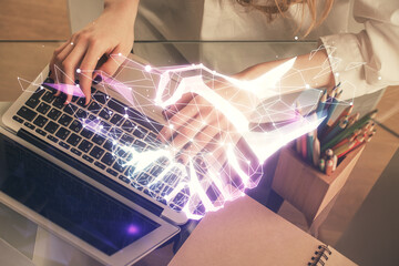 Double exposure of woman hands typing on computer and handshake drawing. Partnership concept.