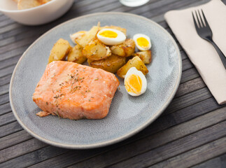 baked salmon fillet with fried potato wedges and quail eggs halves