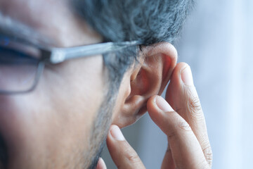 young man having ear pain touching his painful ear ,