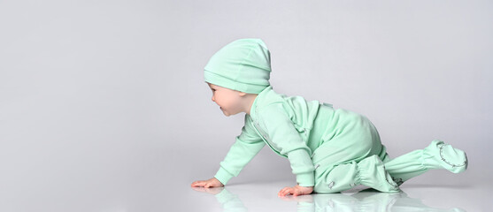 Little baby toddler wearing body set of slider and hat crawling on floor over white background
