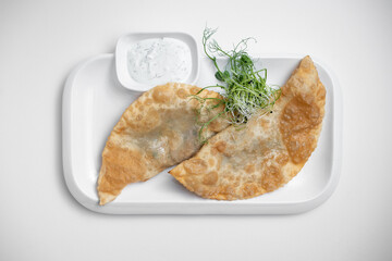 cheburek or fried dough pie with meat feeling and sauce on white background