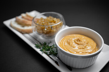 close up of goose liver pate with apple chutneys and bread on black background