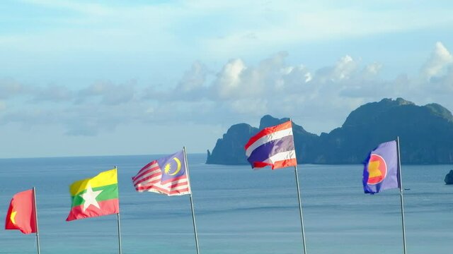 The blowing flags of ASEAN community - Thailand, Malaysia, Vietnam, and  Union of Myanmar -Fluttering freely in sea background, mountains, and blue sky. And beautiful scenery of the island.