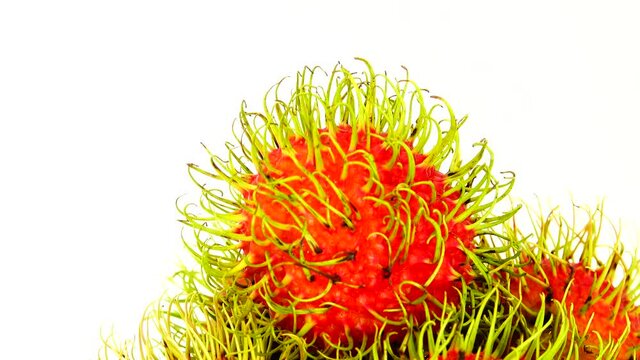 4K  whole red freen color rambutan fruits and one peeled rambutan. Rotating on the turntable isolated on the white background. Close up. Macro