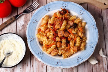 Piatto di fusilli. Pasta italiana condita con verdure miste e  wurstel tagliati a rondelle. Vista dall'alto.